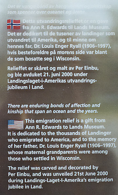Norwegian Emigrant Relief plaque with the Norwegian and also an English translation to "There are enduring bonds of affection and kinship that span an ocean and the years. This emigration relief is a gift from Ann R. Edwards to Lands Museum. It is dedicated to the thousands of Landinger who emigrated to America, and to the memory of her father, Dr. Louis Enger Ryall (1906-1997), whose maternal grandparents were among those who settled in Wisconsin. The relief was carved and decorated by Per Einbu, and was unveiled 21st June 2000 during Landings-Laget-l-Amerika's emigration jubilee in Land."