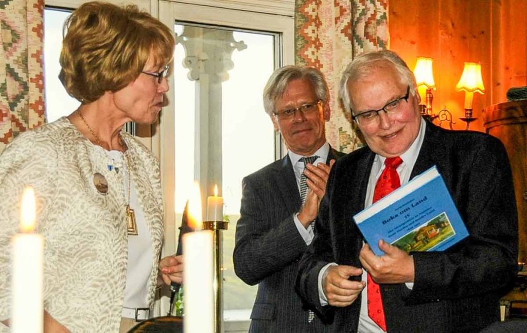 Author and historian Arvid Sandaker receives the first copy of the English translation of his book from Landinglag president and translator Sandra Hendrickson as former ambassador Knut Vollebæk looks on.