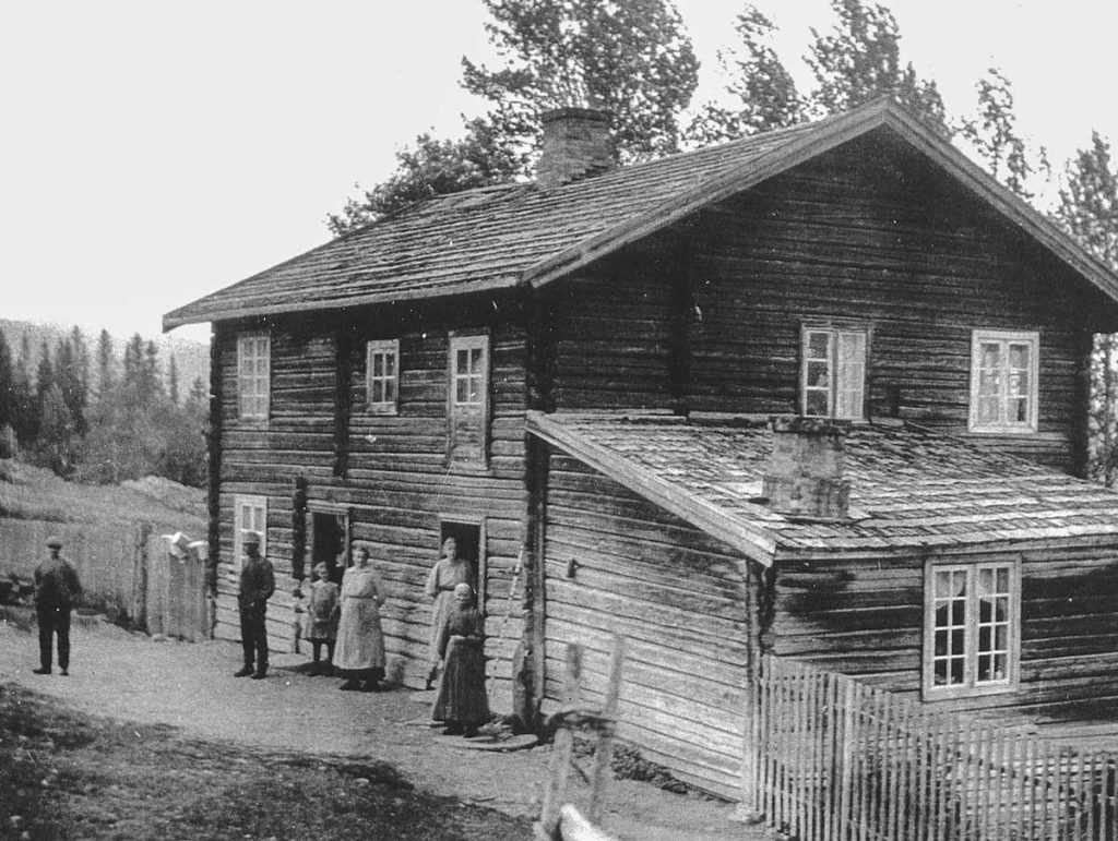 A farm house with people posing in front.